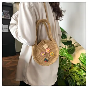 Détail d'un sac rond en paille avec fleurs tissées à la main et bouton en bois naturel