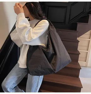 Detailed side view of a large black nylon hobo tote bag on a female model