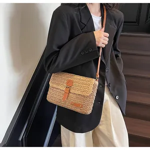 Gedetailleerd overzicht van handgeweven strooien crossbodytas met bruine kunstleren riem