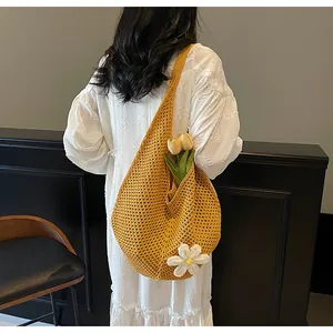 Close-up of yellow crochet tote bag with white flower decor and woven mesh texture