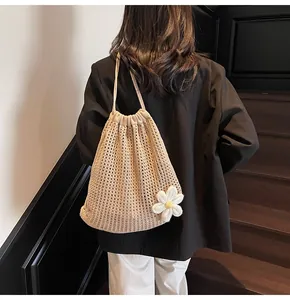 Détail d'un sac à dos en crochet beige ajouré avec fleur de soleil et cordon serrage