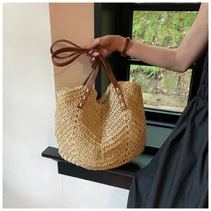 Détail du sac cabas en paille tissé avec anses en cuir marron et coutures en croix