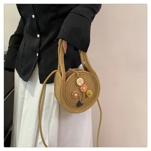 Gros plan détaillé d'un mini sac à main rond en paille avec des fleurs colorées et bandoulière