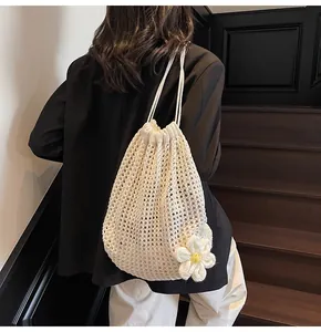 Gros plan détaillé d'un sac à cordon au crochet crème avec une marguerite en relief