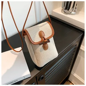 Detail of canvas crossbody bag with wooden toggle closure and brown leather trim accents