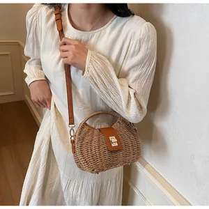 Detailaufnahme der Bohème-Strohtasche mit braunem Lederbesatz und metallischem Drehverschluss