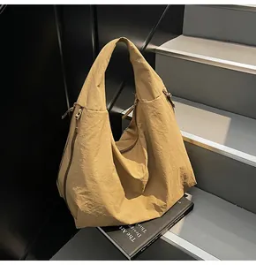 Detail of khaki tote bag showing pleated nylon texture and side zipper structure