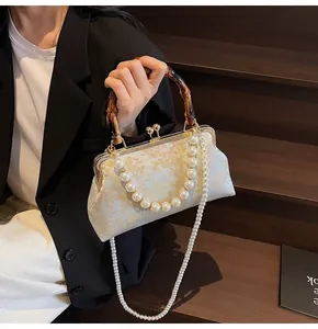 Detail der Vintage-Jacquard-Tasche mit Bambusgriff und Perlenkette mit goldenen Blumenmotiven