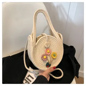Détail d'un sac rond en paille avec fleurs appliquées et fermeture par perle en bois