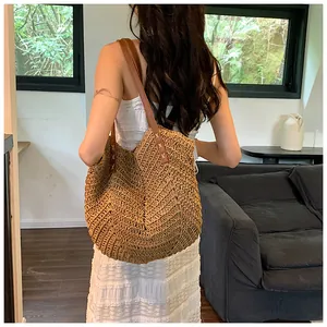 Gros plan sur le tissage en paille en V et les bandoulières en cuir marron du sac