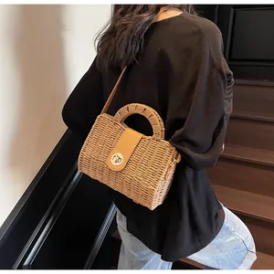 Detailansicht der Stroh-Stofftasche mit Lederriemen und Metallverschluss am Modell