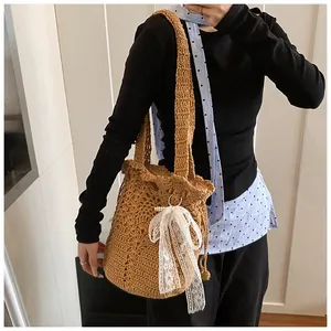 Detail of hand-woven straw bucket bag with floral cutouts and lace bow decoration