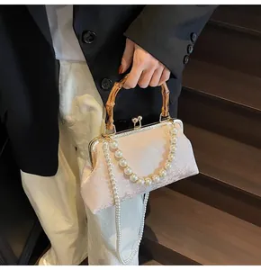 Detailaufnahme der rosa Jacquard-Handtasche mit Bambusgriff und eleganter Perlenkette