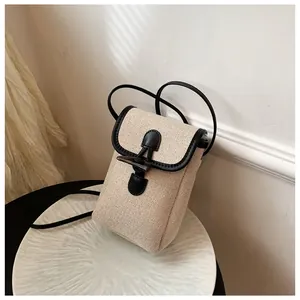Close-up of minimalist canvas crossbody bag with black faux leather trim and horn button