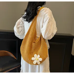 Detail of yellow hollow knit tote bag featuring a white daisy flower and mesh texture
