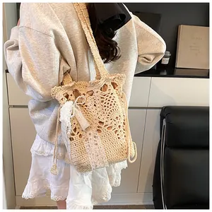 Dettaglio della trama all'uncinetto con fiocco di pizzo e perle su borsa beige