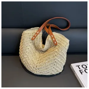 Détail du sac cabas en paille avec texture ondulée beige et sangle en cuir marron à coutures X