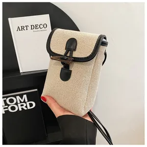 Detailed view of cream canvas phone bag with leather trim and horn button closure