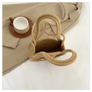 Détail d'un sac à main en paille tressée avec fleurs colorées et doubles anses