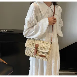 Detail van handgeweven strooien tas met bruine leren riem en stijlvolle klepsluiting
