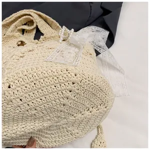 Detailed close-up of cream woven bucket bag featuring lace bow and pearl accents