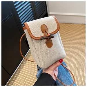 Detail of a vintage mini canvas crossbody bag with toggle button and brown leather trim