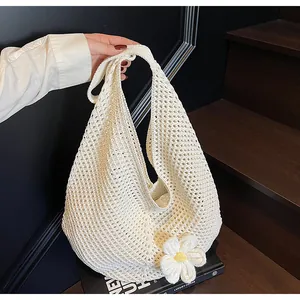 Detail of a beige crochet tote bag featuring hollow knit patterns and a 3D daisy flower charm