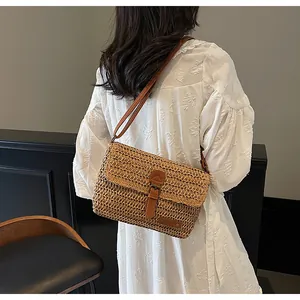 Detail van handgeweven strooien crossbodytas met lederen riem en vintage metalen gesp
