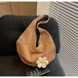 Detail of khaki hollow mesh woven tote with white daisy accent on corduroy sofa