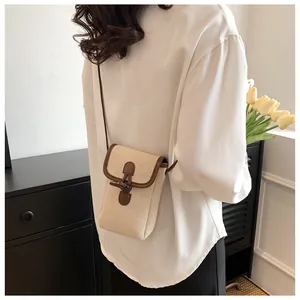 Detail of canvas crossbody phone bag with horn buckle shown on a model