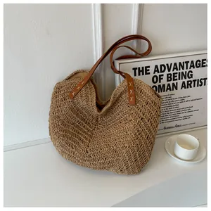 Détail du sac cabas en paille tissé avec anses en similicuir marron et points de croix