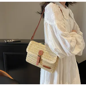 Detail van handgeweven beige rieten tas met bruine lederen bies en metalen sluiting