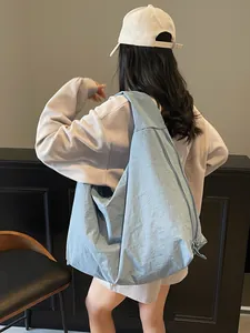 Minimalist large light blue nylon tote bag with zipper shown on model in street setting