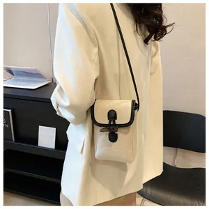 Detail view of canvas crossbody bag featuring wooden toggle closure and leather strap