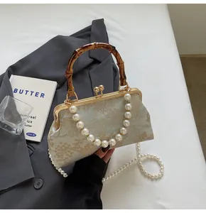 Detail der Jacquard-Handtasche mit Bambusgriff und eleganter Perlenkette im Retro-Stil