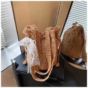 Dettaglio della borsa in paglia intrecciata con fiocco in pizzo e perle eleganti