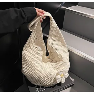 Detail of a beige crochet tote bag featuring a knit daisy flower and hollow texture