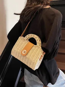 Stroh-Stofftasche mit brauner Lederklappe und Metalldrehverschluss auf Holztreppe