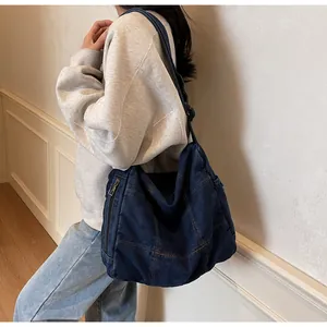 Detail view of washed denim fabric with contrast stitching on large shoulder bag