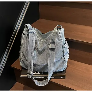 Close-up of light blue washed denim shoulder bag with frayed edges and wide strap