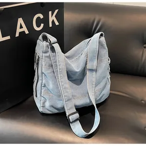 Close-up of washed denim shoulder bag with adjustable strap and side zipper pocket