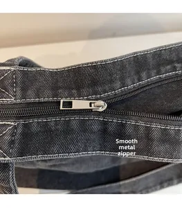 Détails de la fermeture éclair argentée et des coutures sur le sac en jean gris foncé