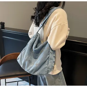 Detail of light blue washed denim shoulder bag with stitching and frayed edges