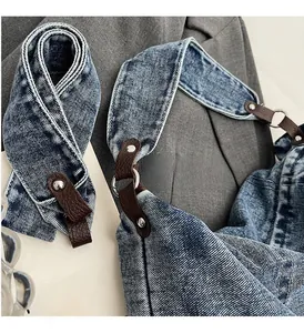 Detail of vintage denim bag with brown leather strap and silver metal hardware accents