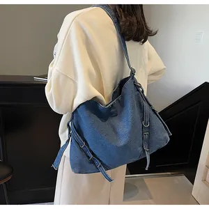 Detail of spacious denim hobo bag showing adjustable metal buckles and texture