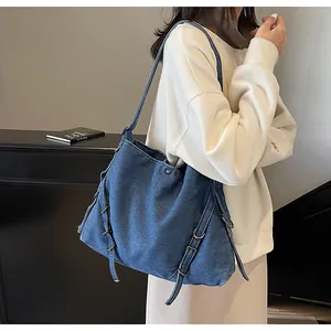 Detail of blue denim tote bag with buckle straps and metal rings for a retro look