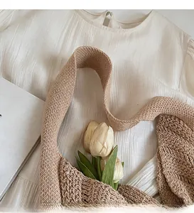 Detailed macro view of wide woven shoulder straps on a light coffee knit shoulder bag