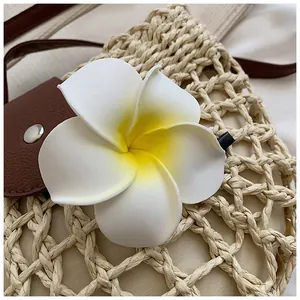 Λεπτομερής κοντινή λήψη κλιπ μαλλιών Plumeria σε μπεζ υφαντή καλοκαιρινή τσάντα