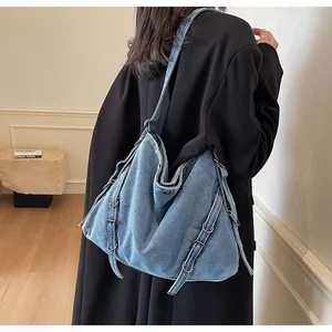 Detail of blue washed denim tote bag with metal buckles and vintage industrial straps