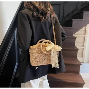 Detailansicht der handgefertigten Strohtasche mit Spitzenschleife und Innenbeutel